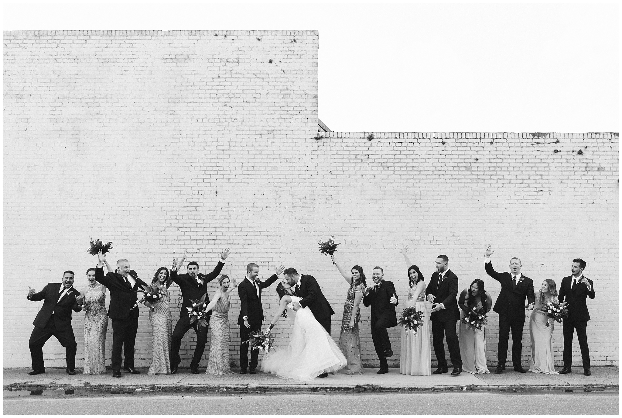 bridal party in front of white wall at the glass factory